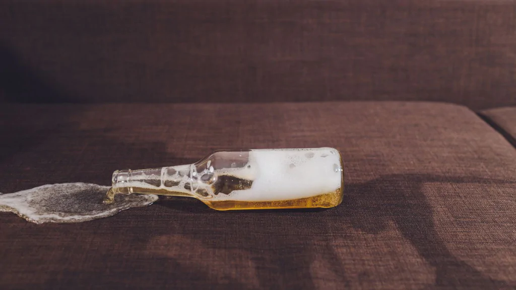 Liquido de garrafa derramando em sofá.