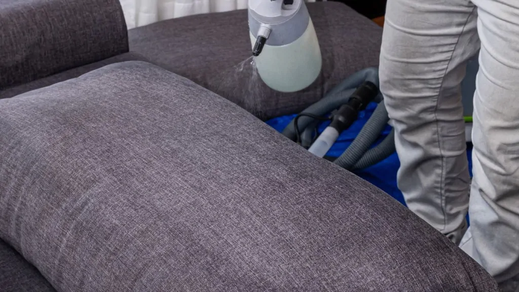 O que é blindagem de sofás: profissional aplicando produto em sofá.
