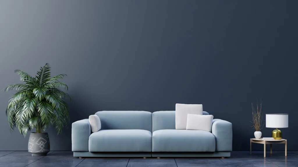 Sofá com planta de um lado e uma mesinha do outro com uma almofada extra.