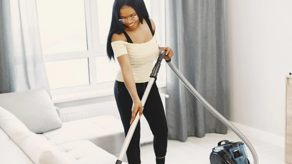 proteger o sofá de cachorros: mulher aspirando sofá.